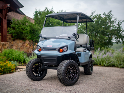 An E-Z-GO Express S4 4 Passenger Golf Cart in front of a log cabin.